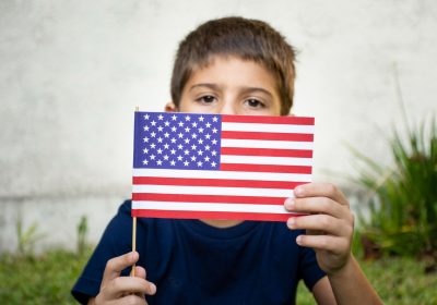 Imagem ilustrativa sobre visto americano para criança mostrando uma criança segurando a bandeira dos Estados Unidos.