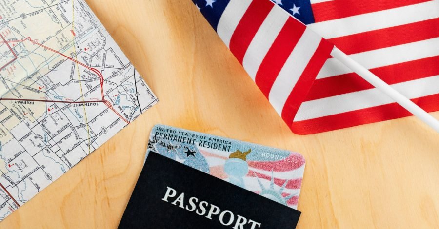 Imagem ilustrativa sobre o prazo para visto americano mostranso um passaporte, passagens aéreas e uma pequena bandeira do país.